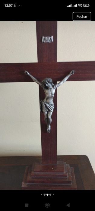 Crucifixo de mesa composto por uma cruz de madeira escura com uma base escalonada de vários níveis.A figura tridimensional do corpo de Cristo (corpus)