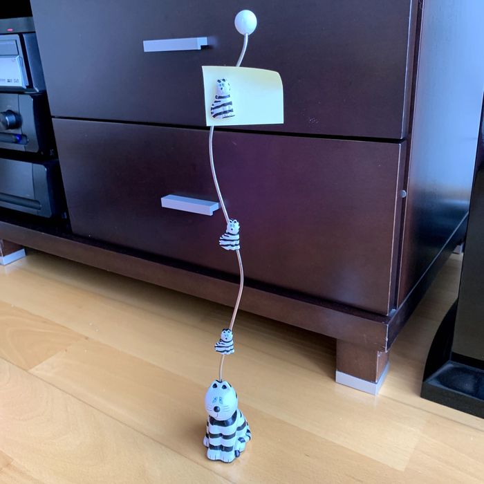 Pisa-papéis com aste vertical e três suportes magnéticos (gatos).