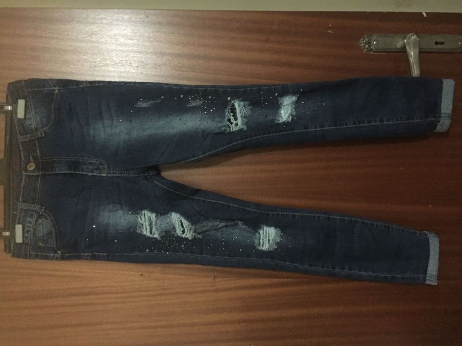 Calças ganga elásticas com rasgões e pinos brilhantes e metálicos M/L