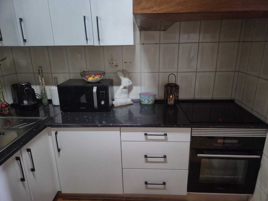 Balcão de cozinha juntamente com armários e um sofá com mesa