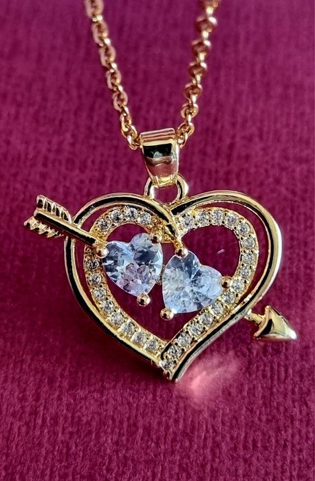 Colar dourado, em aço, com 2 corações unidos por uma flecha.