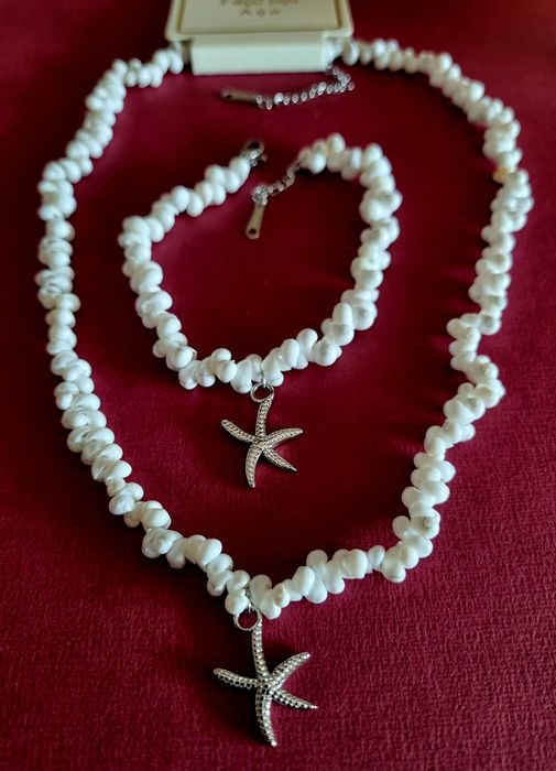 Conjunto branco (colar e pulseira), em aço, com estrela do mar prateada.