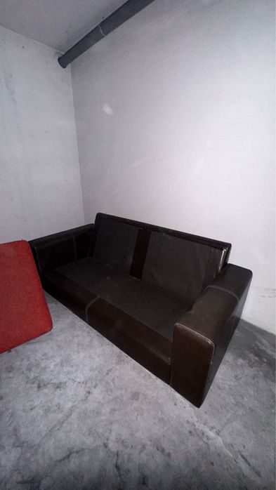 Sofá castanho em pele, com encostos e assentos em almofadas,.