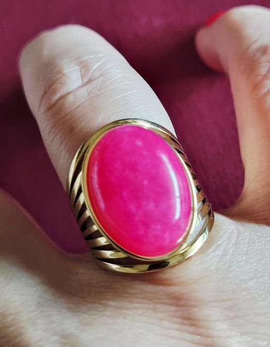 Anel dourado, em aço, com pedra oval rosa fucsia. 18/ajustável