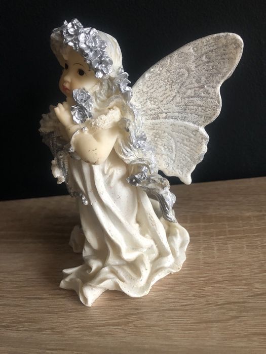 Figurka z żywicy Aniołek z różą i koszem kwiatów w ręku.