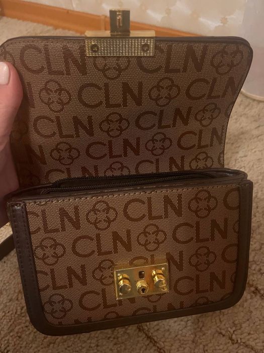 коричневая сумка через плечо с монограммой и золотой фурнитурой.