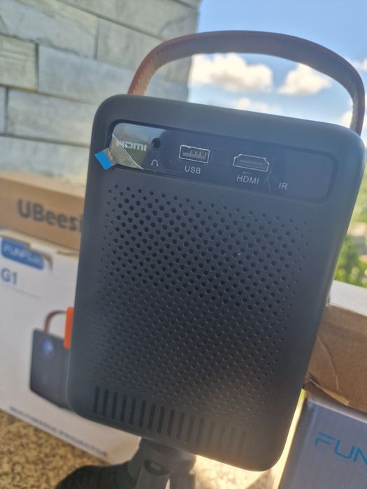 projetor portátil FunFlix G1 com alça de transporte.O dispositivo possui conectividade Wi-Fi 5G oferta de tripé