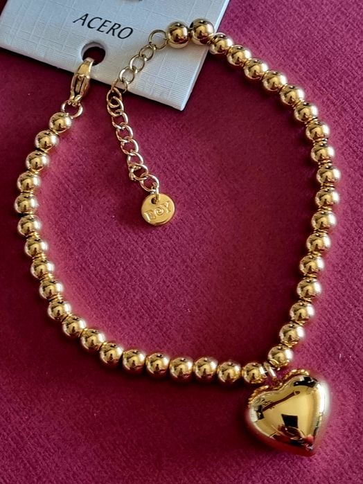 Pulseira dourada, em aço, toda às bolinhas e com 1 coração. Tem extens