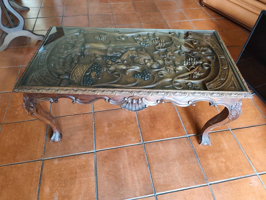 Mesa de centro, ricamente esculpida à mão, com cena de vindima.