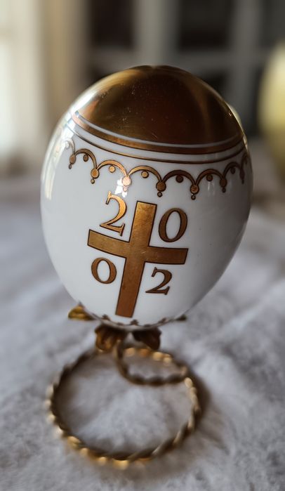 Ovo de Páscoa de porcelana com decorações douradas.Assente num suporte