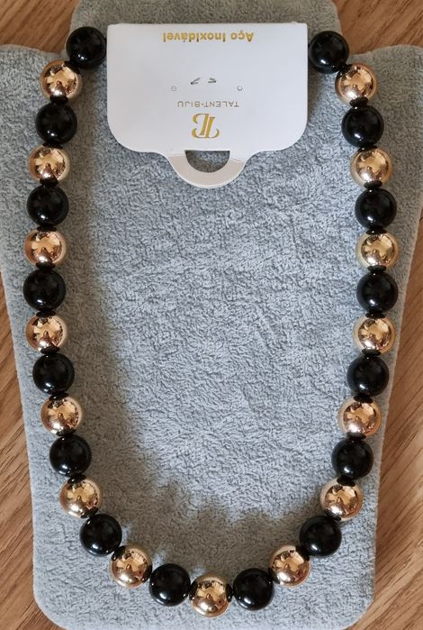 Colar dourado, em aço, às bolinhas douradas intercaladas com pretas. Leve.