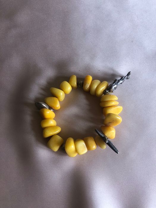 Pulseira com pedras amarelas e elementos metálicos como a estrela e outros