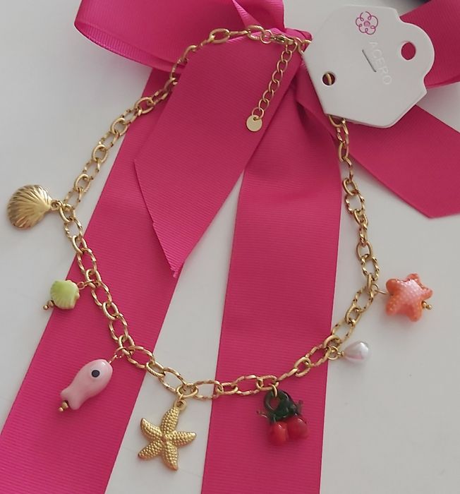 Colar dourado, em aço, com 7 pingentes diferentes. Tem extensor