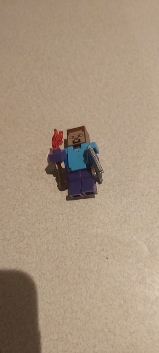 Klocki lego Minecraft Steve z kilofem, zbroją oraz pochodnią.