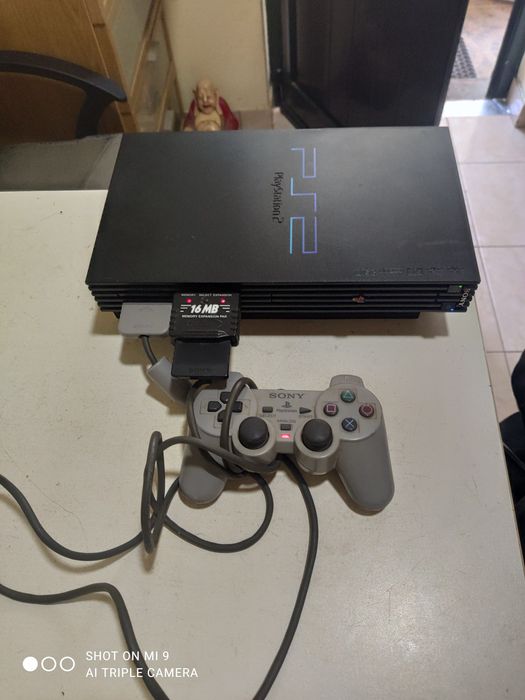 PS2 com comando e um jogo