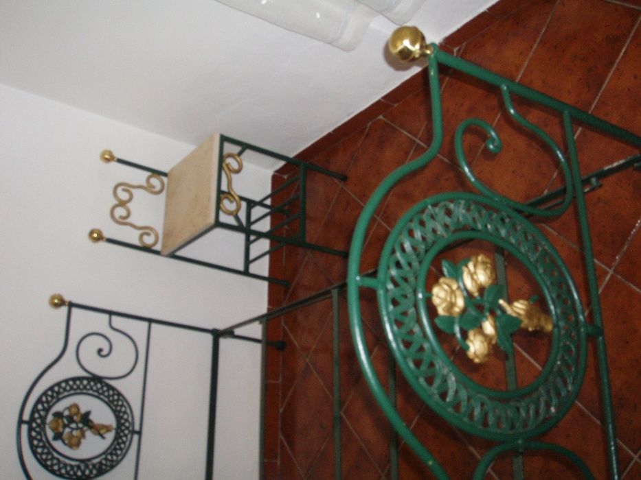 cama de ferro com mesa de cabeceira e candiero de teto