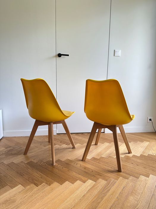 Dwa żółte krzesła na drewnianych nogach skandynawski styl