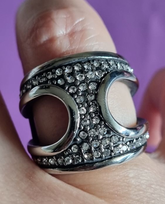 Anel prateado, em aço, aberto dos lados e cheio de zirconias. T17/18