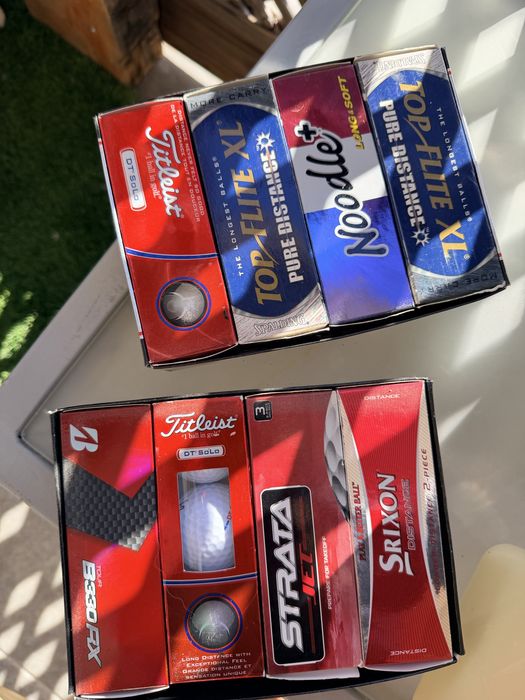 Bolas de golfe novas nas caixas e de treino