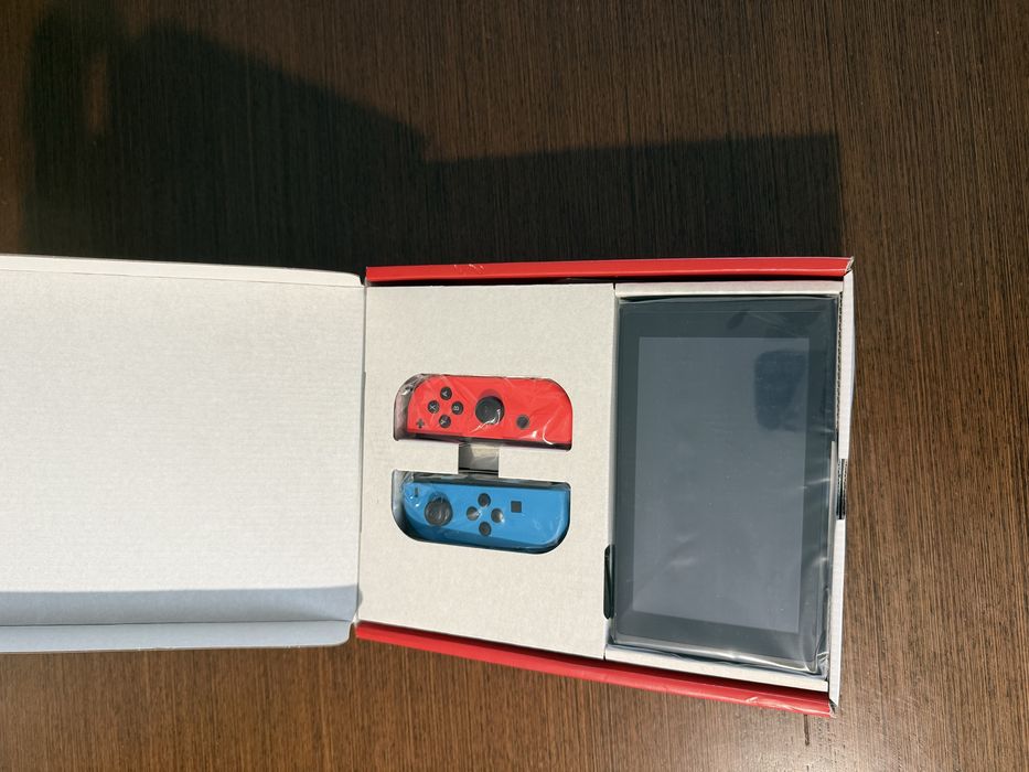 Vendo Nintendo Switch clássica com comandos Joy-Con azul e vermelho, em estado novo.