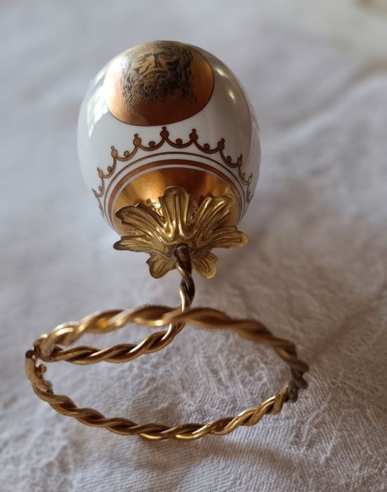 Ovo de Páscoa de porcelana com decorações douradas.Assente num suporte