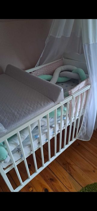 Solidne, białe łóżeczko dziecięce z baldachem.