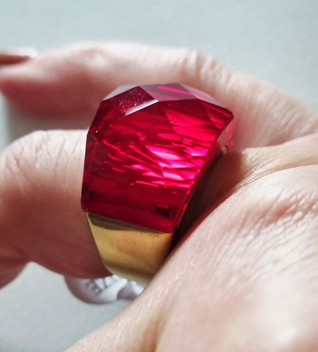 Anel dourado, em aço, com vermelho facetado na parte de cima. T17