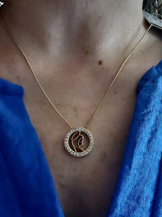 Colar dourado, em aço, com pingente da Nossa Senhora rodeada de zirconias.
