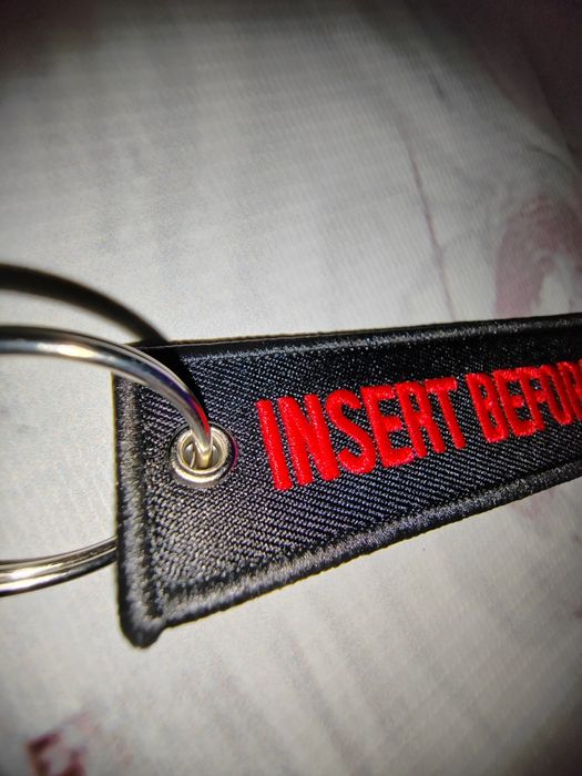 Czarny haft z czerwonym napisem Insert before flight