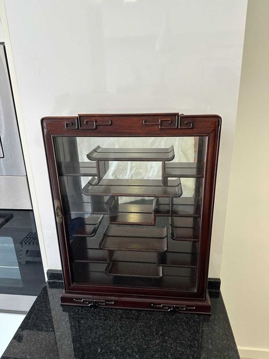 Vitrine expositora em madeira escura com porta de vidro