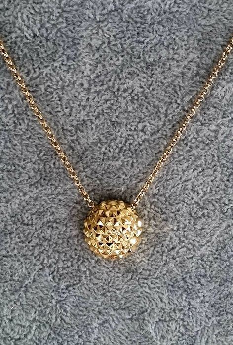 Colar dourado, em aço, com meia bola toda trabalhada. Tem extensor