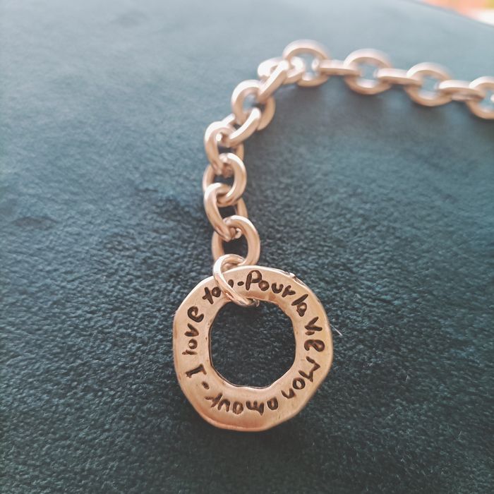 Pulseira em aço prateado com fecho com inscrição.