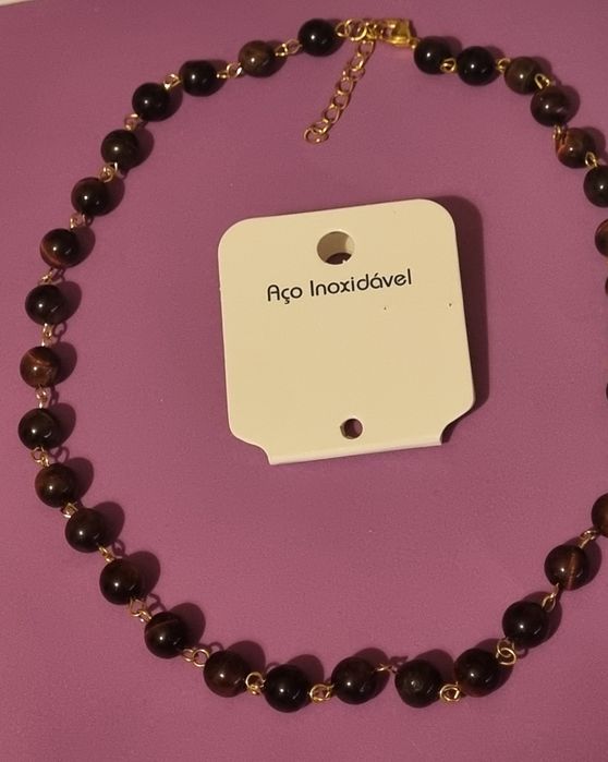 Colar dourado, em aço, às bolinhas castanhas de pedra natural "olho de gato". Tem extensor.