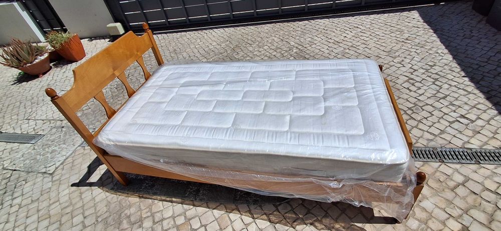 Cama individual em madeira com colchão.