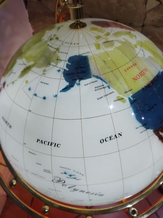 Globo com o mapa do mundo com estrutura em pedra e com base de madeira