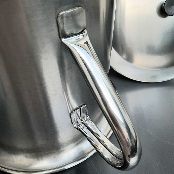 Panela grande industrial em aço inoxidável com tampa e pega.