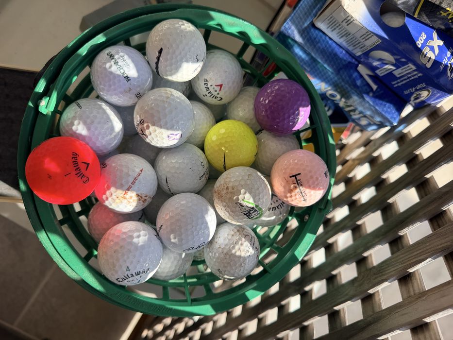 Bolas de golfe novas nas caixas e de treino