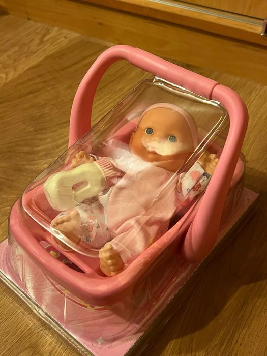 Lalka w nosidełku z butelką