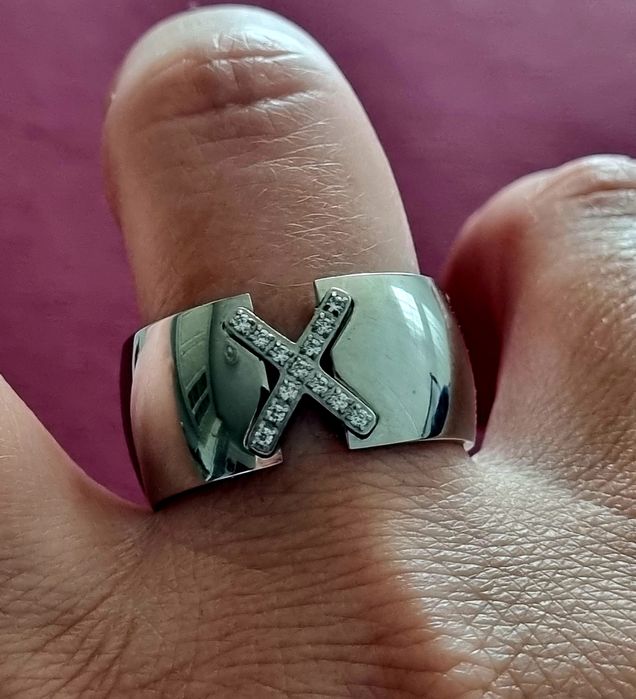 Anel grosso prateado, em aço, com um X em zirconias. T20