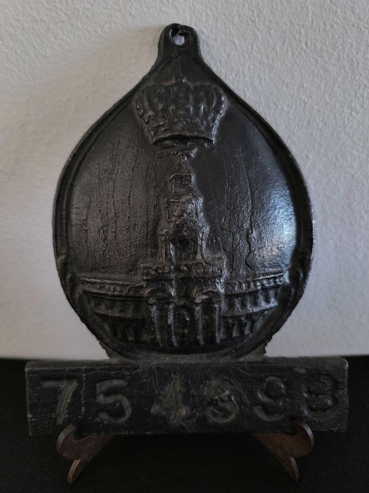 Placa de metal com o n.º 754398, marcada com o emblema da seguradora