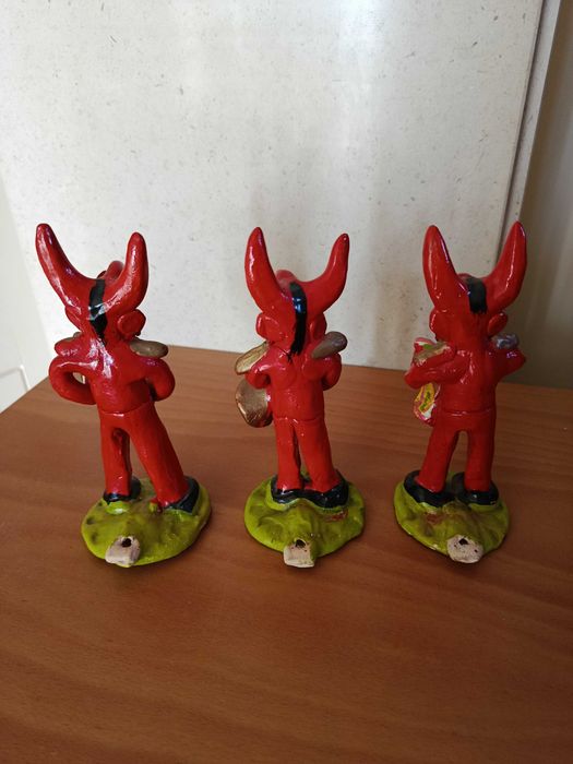 TRÊS diabos vermelhos com instrumentos cujos autores são MC