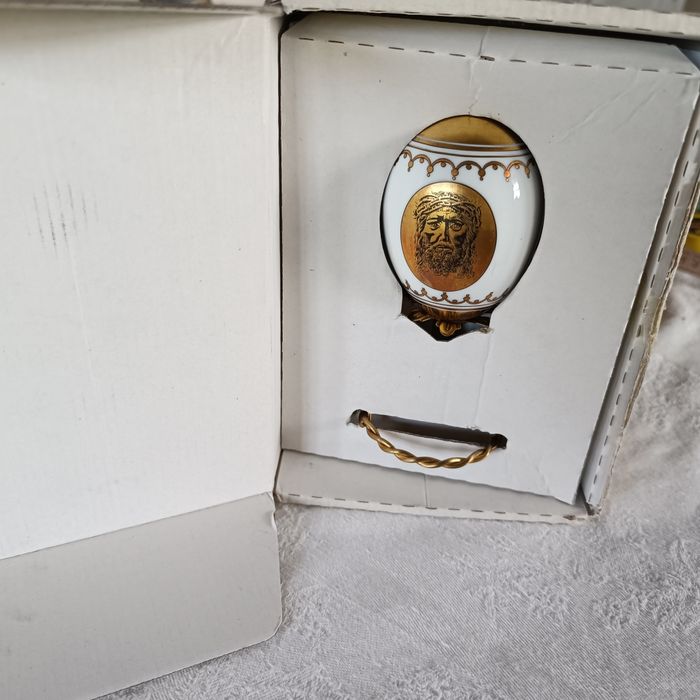 Ovo de Páscoa de porcelana com decorações douradas.Assente num suporte