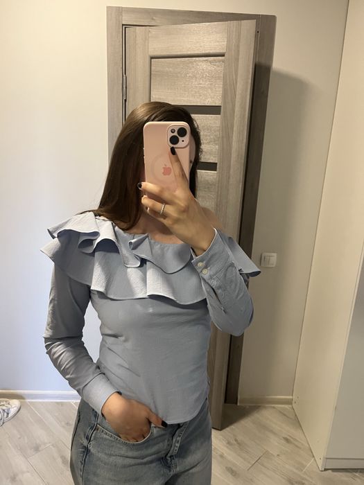 Блакитна блуза з оголеним плечем і обʼємним воланом