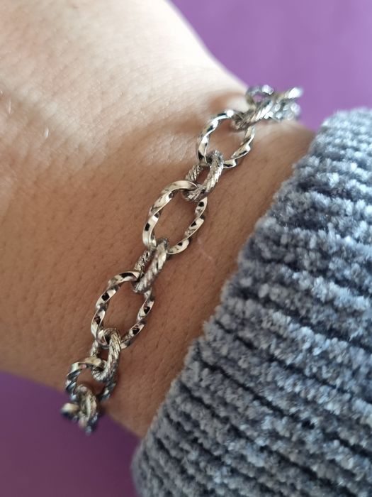 Pulseira prateada, em aço, com elos trabalhados. Tem extensor