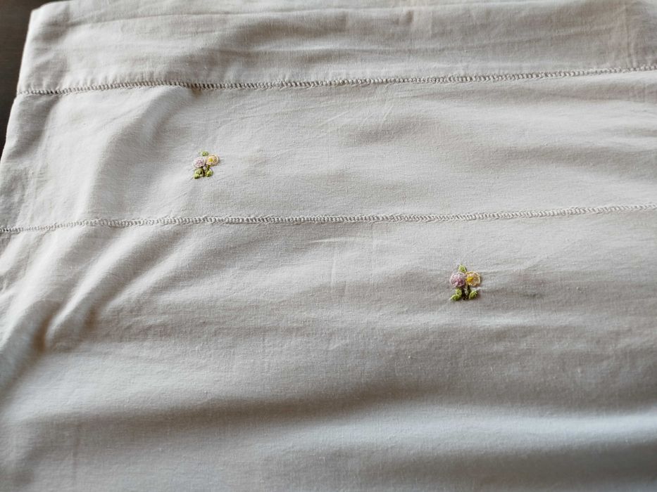 Lençol e almofada com flores bordadas a mão.