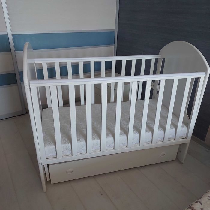 Продам детскую кроватку б/у, белую, с маятником, матрасиком и двумя ящиками .