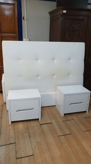 Cama estofada e mesinhas com marcas de uso estrado