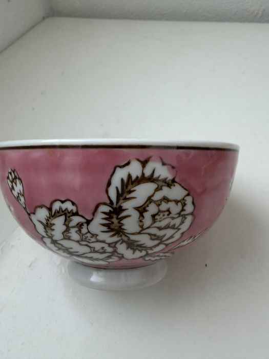 Esta é uma taça de chá cor-de-rosa com estampado de peónias.
