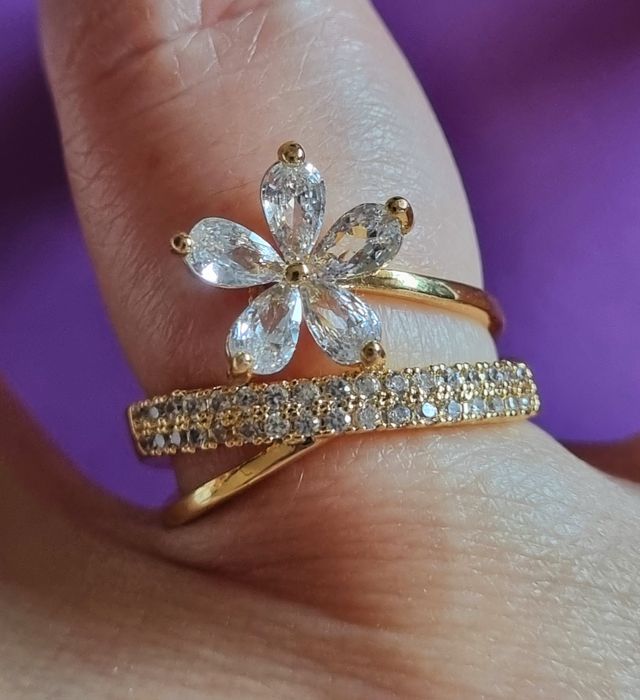 Anel dourado, em aço, com zirconias e uma flor. T17 e T20