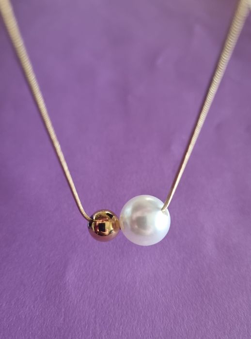 Colar dourado, em aço, com 1 pérola e 1 bolinha dourada móveis.  Tem extensor.